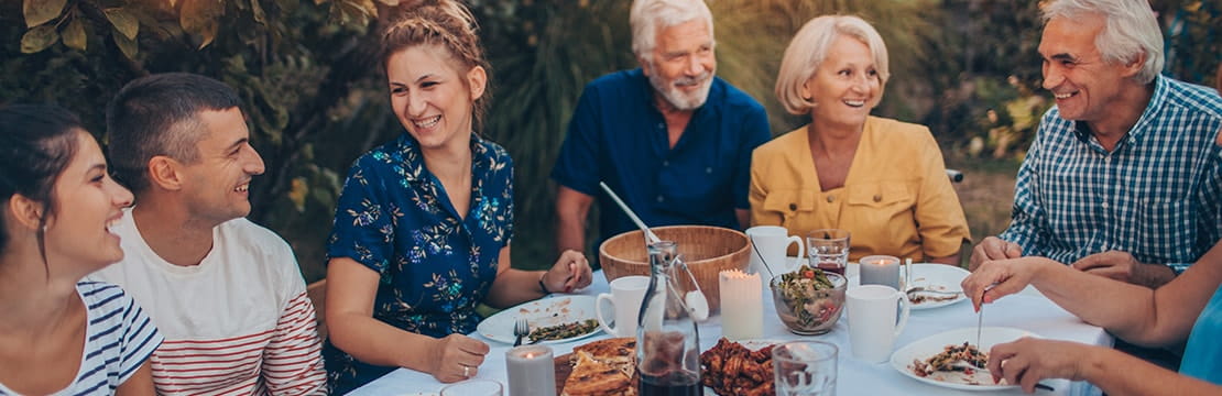 Photo of a multi-generation family having dinner outdoors in their back yard