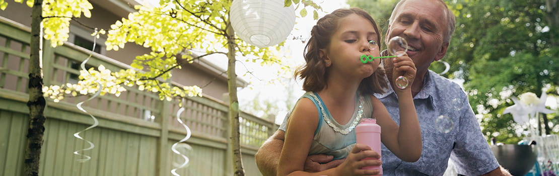 Grandfather watching granddaughter blowing bubbles