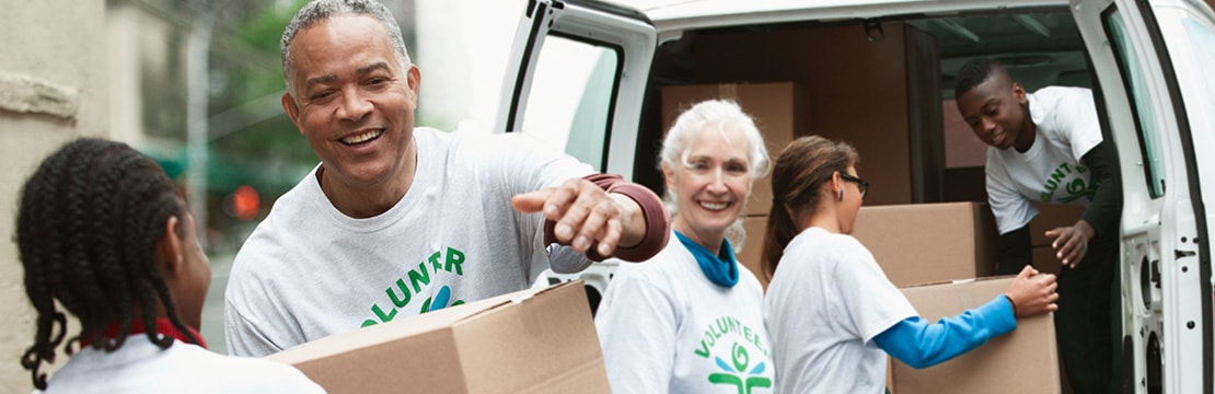Volunteers passing cardboard boxes from delivery van